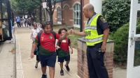 deputy wearing bright yellow traffic share fist bump with a student arriving at school