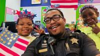 deputy with two children wearing Independence Day decorations and holding handmade U.S. flag