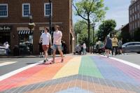 two people walking on rainbow crosswalk