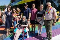 Group of people posing in front of the pride Dash bus