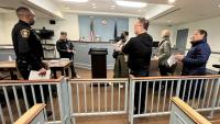 Deputy in blue uniform speaking with several civilians in a courtroom