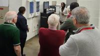 Deputy in civilian clothing explaining the livescan computer for fingerprinting to a group of community members in the jail