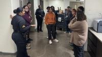 Sheriff's sergeant in a blue uniform giving a tour of the jail to several civilians