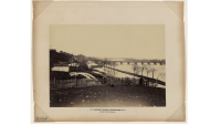 Photograph showing three men in Georgetown in the foreground with the Aqueduct Bridge and C&O Canal in the background.