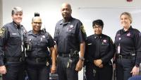 Five deputies wearing pink badges on their blue uniforms in support of Breast Cancer Awareness Month