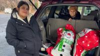 Woman and child at a car with large holiday gift bags inside
