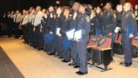 Two rows of new deputies, some in blue uniforms and some in tan, holding up their right hands and taking an oath at a ceremon
