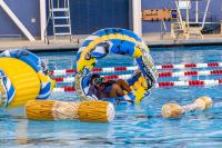 Pool toys and blow ups on the water, while a child is inside one of the blow up wheel