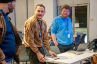 Photo of three men talking and handling paperwork