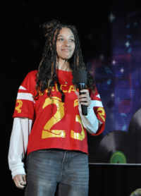 Teen girl dressed in football jersey and white long sleeve undershirt holding a mike