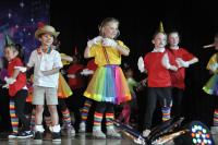 Kids dressed like puppets in colorful clothing on stage smiling