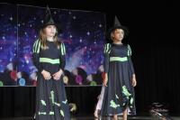Two girls dressed like witches with black pointy hats and black dressed with green accents