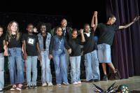 Kids holding hands in jeans and black on stage