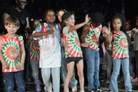 Kids in tie dye waving and smiling at the crowd