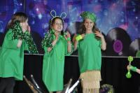 Three young girls on the stage dressed in green clothing and accessories