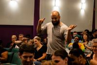 A man is standing among the seated crowd dancing