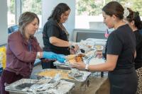two women serve food to employees