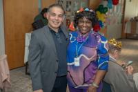 man in grey suit and woman with flower crown standing arm in arm, smiling at each other