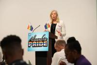 Speaker on stage with Alexandria Pride sign