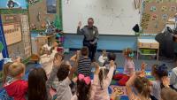 Hands go up as students join a classroom conversation with an APD officer during Faith & Blue’s Books & Badges activities.