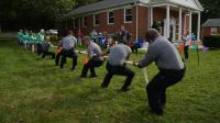 APD officers pull together during a spirited tug-of-war at Alexandria Free Methodist Church, with community members cheering from the sidelines.