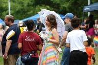 Person in rainbow dress holding parasol at Alexandria Pride 2026