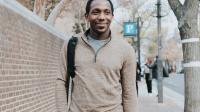 A photo of a commuter with a backpack and tote bag walking down King Street