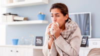 woman at home looking sick with a tissue in her hands about to sneeze