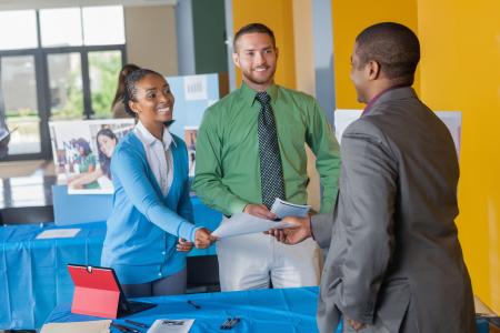 Photo of a job seeker receiving information from two representatives at a job fair