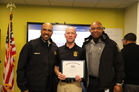 Lt. Mike May poses with two other police personal with his graduation certificate. 