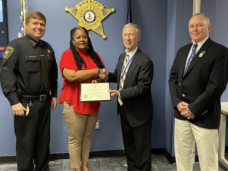 sheriff in uniform and two citizens presenting civilian commander with award