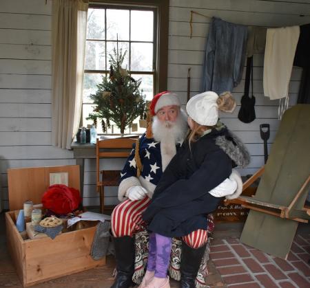 Child sitting on santa's lap, in Civil War hut.
