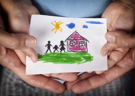 Hands holding child drawing of family