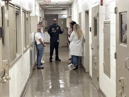 Sheriff's Office commander in blue uniform giving tour to several community members inside the jail