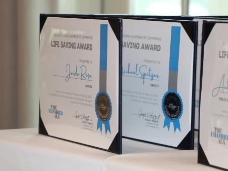 Life saving awards certificates with silver and blue details and standing up on a table