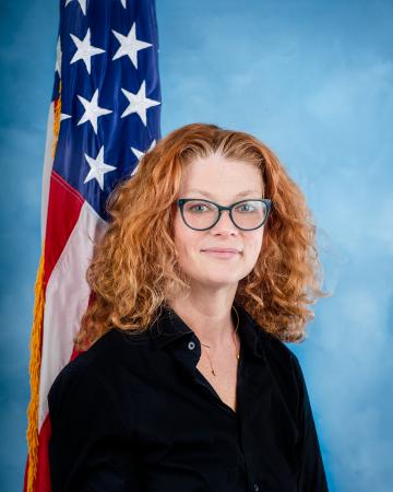 woman smiling at camera with american flag and blue background