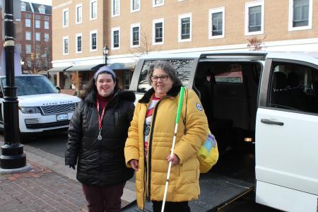 An image of two women standing next to an accessible minivan on a brick sidewalk.
