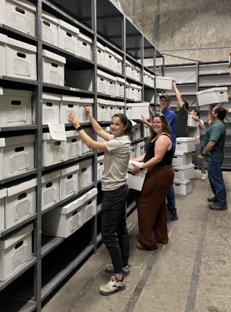 Archaeologists move labeled boxes onto metal shelving in the City of Alexandria's collection facility.