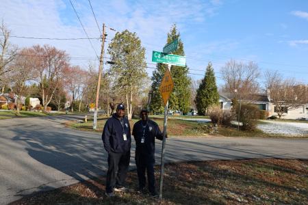 Two men stand under a newly installed street sign for Robert L. Bob Calhoun Ave.