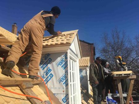 Roofer installing shingles on dormer.