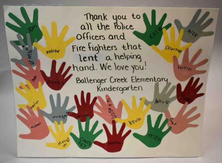A poster from a kindergarten class reads, “Thank you to all the Police Officers and Firefighters that lent a helping hand. We love you! Ballenger Creek Elementary Kindergarten.” The words are bordered with 22 traced hands with names of the students.