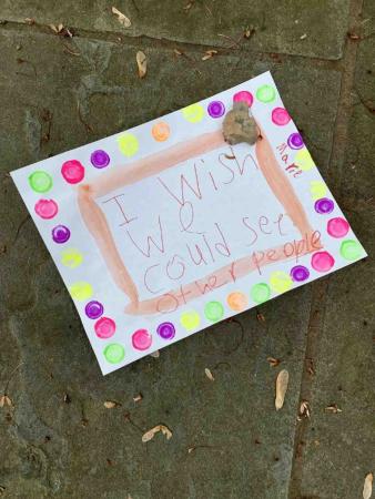 A child’s colorful sign reads, “I wish we could see other people. Marie.”