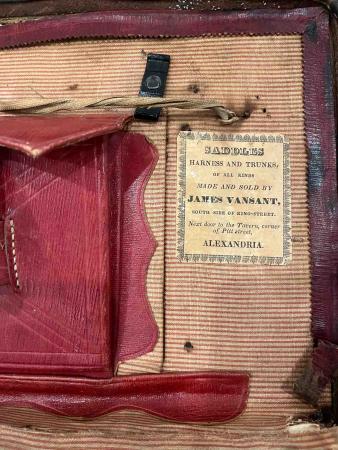 A label on the inside of a trunk, to the right of a red pocket, reads, “SADDLES/HARNESS AND TRUNKS/of all kinds/MADE AND SOLD BY/JAMES VANSANT/South side of King-Street/Next door to the Tavern, corner/of Pitt street,/ALEXANDRIA”