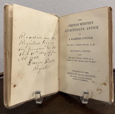 The book "The Christian Minister’s Affectionate Advice to a Married Couple" is open to the title page and a handwritten inscription records the marriage.