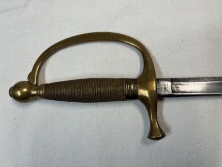 The brass hilt of the sword, with a mark on the top of the steel blade.