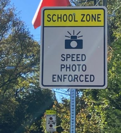 A road sign showing a camera with text saying Spped Photo Camera Enforce.