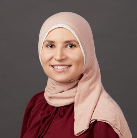 woman smiling at camera with burgundy shirt and light pink head covering