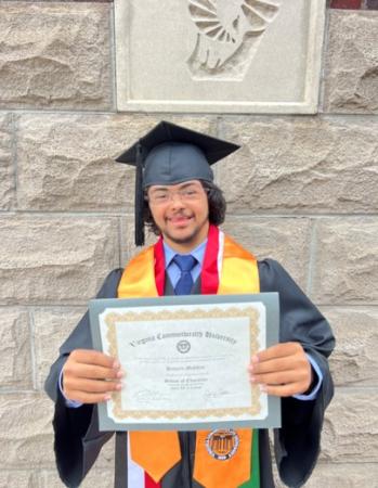 DCHS client Hussein holding a framed diploma certificate from Virginia Commonwealth University