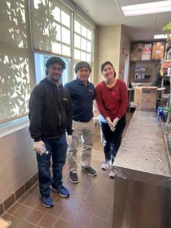 Hussein and two volunteers, with hairnets, working in the food kitchen.