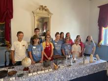 Group of teenagers standing behind a table with chocolate making supplies in ballroom